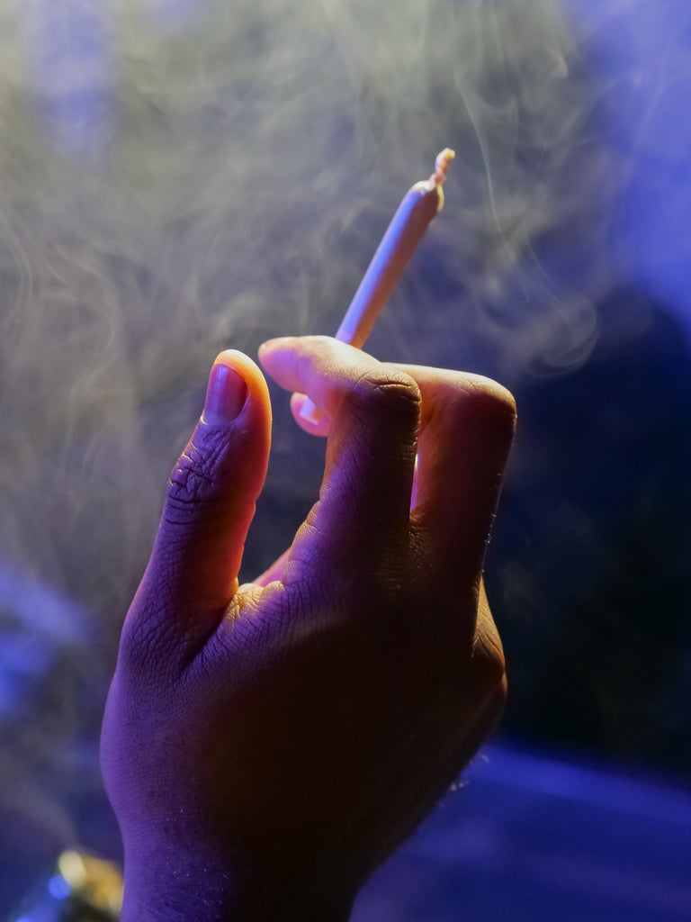 Hand holding pre-rolled joint with smokey background