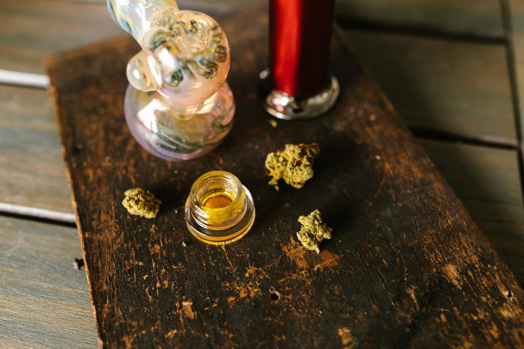 Jar of concentrate and cannabis on wooden tray